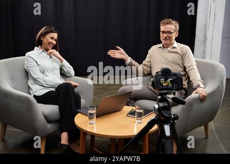 Eine Journalistin mittleren Alters setzt sich in einer professionellen Interviewatmosphäre mit einem männlichen Experten zusammen. Stockfoto