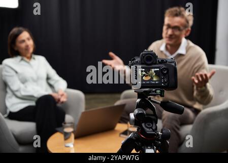 Eine Journalistin mittleren Alters engagiert einen Experten während eines professionellen Interviews in einem modernen Studio. Stockfoto