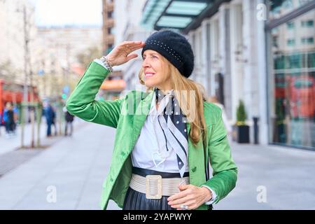 Frau mittleren Alters, elegant gekleidet, mit Hut und grünem Blazer. Stockfoto