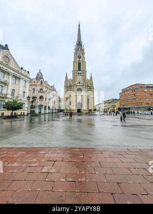 Regentag in Novi Sad: Menschen auf dem Stadtplatz und das Wahrzeichen - Name der Marienkirche Oktober 2024 Serbien Stockfoto