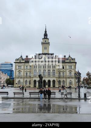 Menschen, die während des Regentages laufen, Bänke am Rathaus auf dem Freiheitsplatz, Novi Sad, Serbien, Oktober 2024 Stockfoto