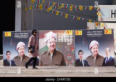 Duhok, Irak. Oktober 2024. Eine Frau läuft an Spruchbändern des Präsidenten der Kurdischen Demokratischen Partei (KDP/PDK) Masoud Barzani vor den Wahlen zum Kurdischen Regionalparlament in Duhok, Irak, vorbei. (Foto: Ismael Adnan/SOPA Images/SIPA USA) Credit: SIPA USA/Alamy Live News Stockfoto