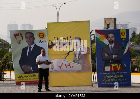 Duhok, Irak. Oktober 2024. Ein Mann steht neben der Straße, vorbei an Wahlbändern des Kandidaten der Kurdischen Demokratischen Partei (KDP/PDK) und einem Bild des Vizepräsidenten der Partei Masrour Barzani vor den Wahlen zum Kurdischen Regionalparlament in Duhok, Irak. (Foto: Ismael Adnan/SOPA Images/SIPA USA) Credit: SIPA USA/Alamy Live News Stockfoto
