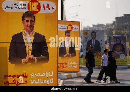 Duhok, Irak. Oktober 2024. Die Menschen gehen an Wahlbändern der Kandidaten der Kurdischen Demokratischen Partei (KDP/PDK) und anderen vorbei, die Bilder des Vizepräsidenten der Partei Nechirvan Barzani vor den Wahlen zum Kurdischen Regionalparlament in Duhok, Irak, tragen. (Foto: Ismael Adnan/SOPA Images/SIPA USA) Credit: SIPA USA/Alamy Live News Stockfoto