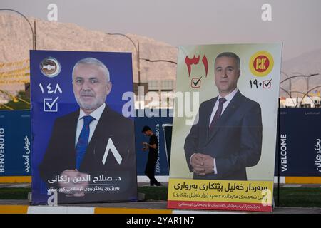 Duhok, Irak. Oktober 2024. Ein junger Mann läuft am Straßenrand vorbei an Wahlbändern der Kandidaten der Kurdischen Demokratischen Partei (KDP/PDK) (R) und der Kurdischen Islamischen Union (L) vor den Wahlen zum Kurdischen Regionalparlament in Duhok, Irak. (Credit Image: © Ismael Adnan/SOPA Images via ZUMA Press Wire) NUR REDAKTIONELLE VERWENDUNG! Nicht für kommerzielle ZWECKE! Stockfoto