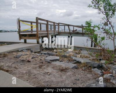 Seitenansicht beschädigte Holzbrücke am späten Nachmittag. Gulfport Florida Beach. Betonsteig und Sanderosion an der Boca Ciega Bay nach starker Belastung Stockfoto