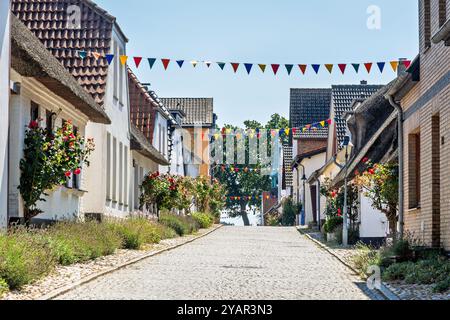 Straße mit alten Fischerhäusern, dekoriert mit bunten Girlanden in Maasholm an der Schlei in Deutschland im August Stockfoto