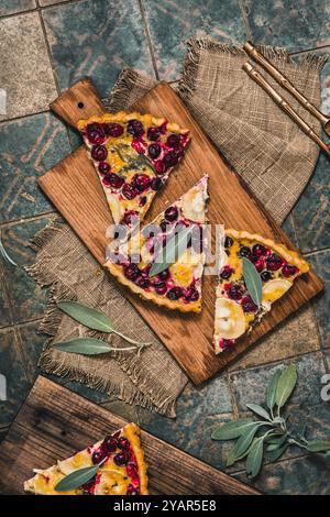 Stücke einer Preiselbeerziegenkäse-Tarte mit Salbei auf rustikalem Hintergrund, Draufsicht Stockfoto