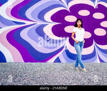 Schöne junge asiatische Frau Wind geblasenes Haar stehend Retro 60er Jahre Stil Fototapete Violett Rosa Blau weiß Kopie Raum Stockfoto