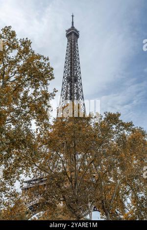 Bäume mit Herbstlaub bedecken teilweise den berühmten Eiffelturm in Paris, Frankreich, in der Herbstsaison Stockfoto
