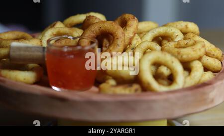 Knusprige Zwiebelringe mit würziger Dipping Sauce auf Holzplatte Stockfoto