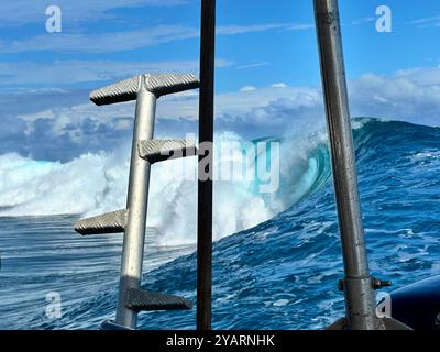 Von einem Wassertaxi aus blickt man auf eine riesige Welle in Teahupo'o, Tahiti, dem Austragungsort des Surf-Events 2024 bei den Olympischen Spielen. Stockfoto