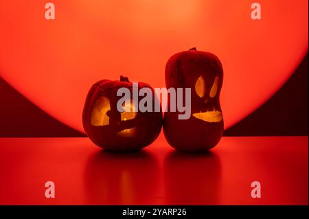 Zwei Jack-o-Laternen leuchten im Dunkeln auf rotem Hintergrund. Halloween Dekoration. Stockfoto