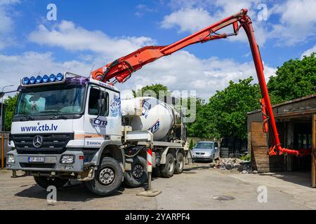 Liepaja, Lettland, 06. Juni 2024: Gießen von frischem Beton in Innenräumen mit moderner mobiler Mischer-Lkw-Pumpe mit langem ausfahrbarem Arm und Schlauch Stockfoto