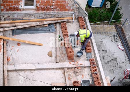 Bauarbeiter bereiten Zement und Mörtel für den Bau von Ziegelmauern vor. Maurer bauen ein Haus aus Bausteinen und Putz. Stockfoto