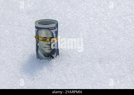 Rollen Sie von uns Dollar-Banknoten auf der Schneeoberfläche Stockfoto