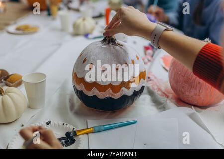 Kinder und Erwachsene malen Kürbisse für Halloween und genießen gemeinsam eine lustige und kreative Aktivität. Hochwertige Fotos Stockfoto