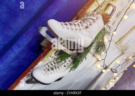 Ein Paar Retro-Schlittschuhe hängt am Türgriff vor dem Hintergrund der Neujahrs- oder Weihnachtsdekoration Stockfoto