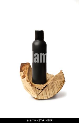 Eine schwarze Plastikflasche auf einem Stück Baumstamm auf weißem Hintergrund mit Kopierraum Stockfoto