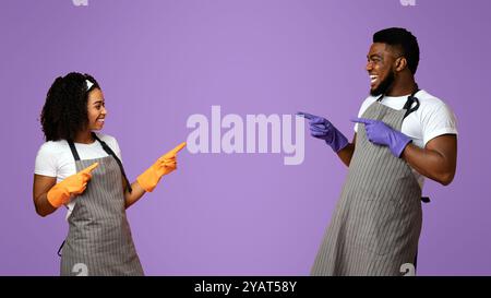 Fröhliche Afrikanischen Paar In Schürzen Und Gummihandschuhe Zeigen Sich Gegenseitig Stockfoto