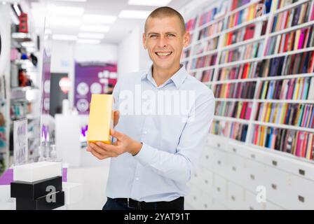 Positiver Mann hält Box für Telefon im Multimedia-Shop Stockfoto