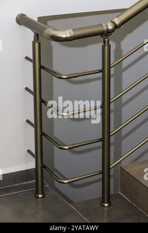 Ein eleganter Handlauf aus Metall mit einzigartigem Design ergänzt die glatte Treppe und unterstreicht die moderne Ästhetik des städtischen Innenraums in nat Stockfoto