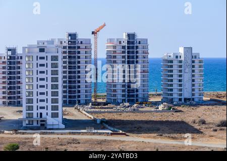 Hoch aufragende Gebäude erheben sich inmitten einer sandigen Küste und glitzerndem Wasser und betonen die Mischung aus Natur und urbaner Architektur unter klarem Himmel. Stockfoto
