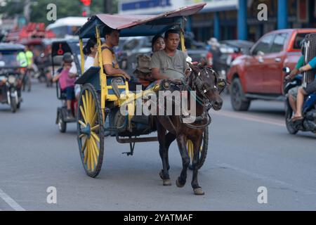 Ein Pferd und eine Kutsche mit Fahrgästen im Heck. Lokal bekannt als „Kalesa“ ist dieser alte Transportstil immer noch in den älteren Stadtgebieten zu finden Stockfoto