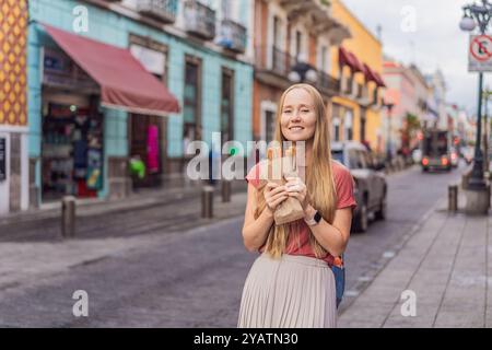 Weibliche Touristen essen Churros auf einer Kolonialstraße in Puebla, Mexiko. Kulturelles Erlebnis, lokale Küche und Streetfood-Konzept Stockfoto