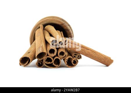 Eine Kollektion aromatischer Zimtstangen, die elegant in einer kleinen Holzschale angeordnet sind und die natürliche Textur und warme Farbe auf einem makellosen weiß präsentieren Stockfoto