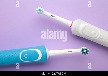 Zwei moderne elektrische Zahnbürsten auf violettem Hintergrund. Draufsicht. Zahnpflege. Minimalismus Stockfoto