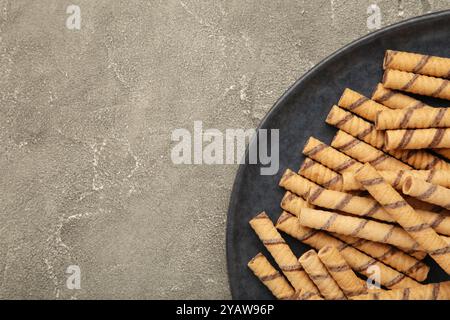 Kaffeewafer-Stick-Rolle mit Kaffeesahne auf einem Teller auf grauem Hintergrund. Leerzeichen für Text Stockfoto