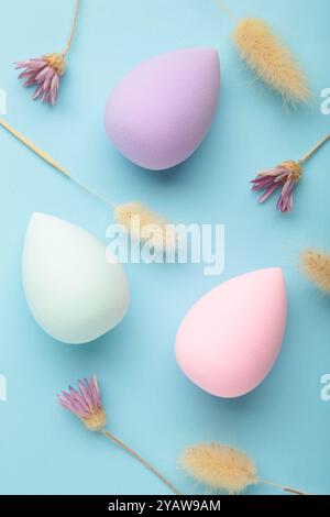 Make-up - Schwamm mit trockenen Blüten auf blauem Hintergrund. Draufsicht Stockfoto