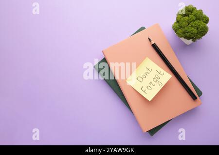 Notizblock und Haftnotizen mit Wort auf violettem Hintergrund nicht vergessen. Draufsicht Stockfoto