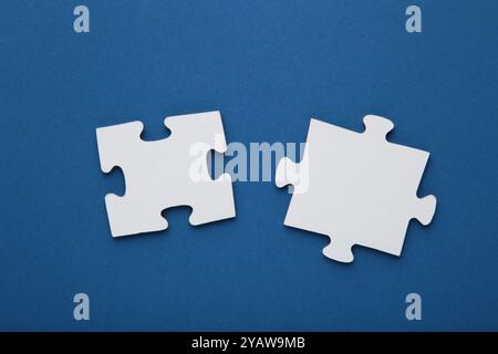 Zwei leere weiße Puzzleteile auf blauem Hintergrund. Draufsicht Stockfoto