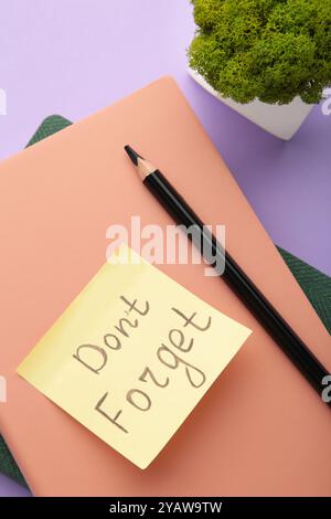 Notizblock und Haftnotizen mit Wort auf violettem Hintergrund nicht vergessen. Draufsicht Stockfoto