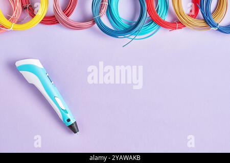 3D-Stift und farbenfrohes Filament für 3D-Druck auf violettem Hintergrund. Perfekt für den Prozess des 3D-Drucks und die Kreativität, die er ermöglicht Stockfoto