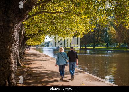 Bedford, England - 7. Oktober 2024: Ein Paar spaziert entlang des Embankments bei Herbstsonne auf dem Fluss Great Ouse in der Stadt Bedford, England Stockfoto