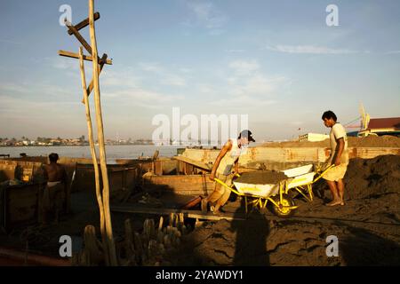 Arbeiter, die Sand am Ufer des Musi-Flusses in Palembang, Süd-Sumatra, Indonesien, entladen. Stockfoto