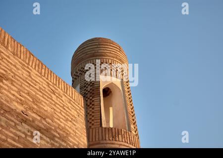 Dieses antike Minarett, hoch neben einem alten Gebäude in der historischen Stadt Chiwa, Usbekistan, ist ein bemerkenswertes Symbol für den reichen Kult der Region Stockfoto