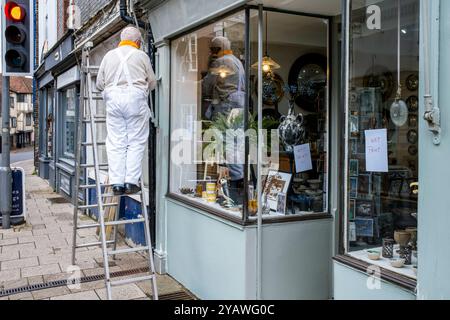 Ein Senior Mann, der Einen Außenbereich Eines Ladens malte und dekorierte, High Street, Lewes, East Sussex, Großbritannien. Stockfoto