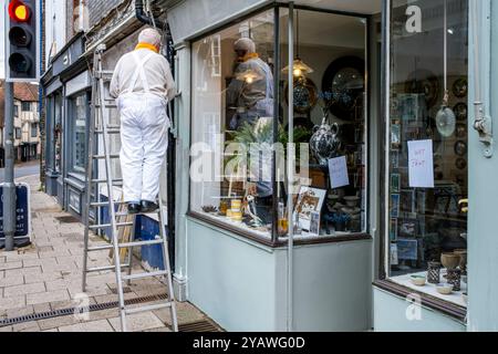 Ein Senior Mann, der Einen Außenbereich Eines Ladens malte und dekorierte, High Street, Lewes, East Sussex, Großbritannien. Stockfoto