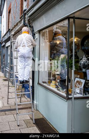 Ein Senior Mann, der Einen Außenbereich Eines Ladens malte und dekorierte, High Street, Lewes, East Sussex, Großbritannien. Stockfoto