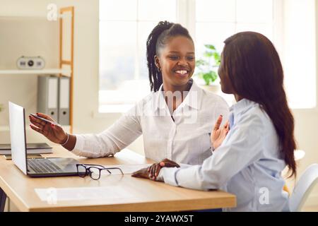 afroamerikanische Büroangestellte, Frauen, die an einem neuen Projekt kooperieren, auf Monitor zeigen Stockfoto