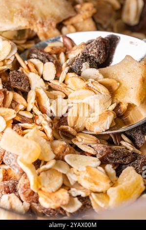 Nahaufnahme einer Schüssel Müsli mit einem Esslöffel darin. Gesundes Frühstückszerealien mit getrockneten Früchten. Stockfoto