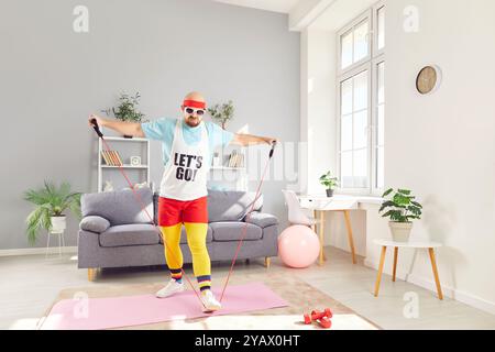 Lustiger junger Mann in Sportbekleidung, der Heimtraining macht, mit Gummiband Dehnungsübungen. Stockfoto