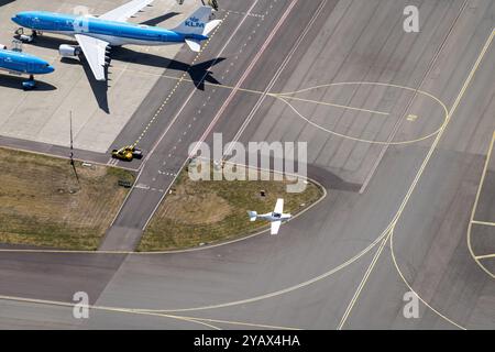 Am internationalen Flughafen Amsterdam fliegt ein kleines Flugzeug, ein Dynamic mit der Zulassung PH-4B7, auf dem Rollweg an einem großen KLM Airbus A330 vorbei. Es bietet einen schönen Kontrast zwischen großen und kleinen Flugzeugen der allgemeinen Luftfahrt. Luft-Luft-Foto. niederlande aus - belgien aus Stockfoto