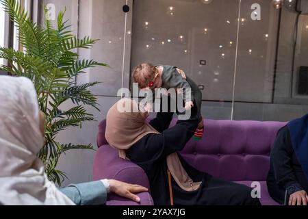 Zwei Frauen in Hijabs und ein Kind, das zusammen in einem Café sitzt, Gespräche teilt und Kaffee genießt. Die Szene zeigt ein warmes, familienfreundliches Atmosp Stockfoto