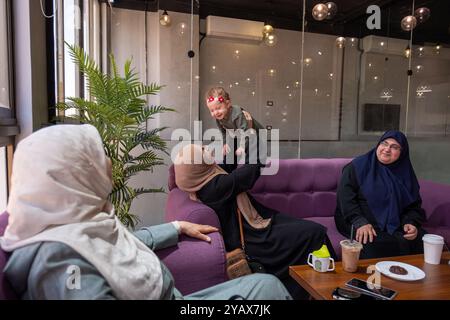 Zwei Frauen in Hijabs und ein Kind, das zusammen in einem Café sitzt, Gespräche teilt und Kaffee genießt. Die Szene zeigt ein warmes, familienfreundliches Atmosp Stockfoto