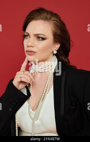 Eine schöne Frau, elegant gekleidet, erwägt einen Moment, strahlt Selbstvertrauen und Anmut aus. Stockfoto